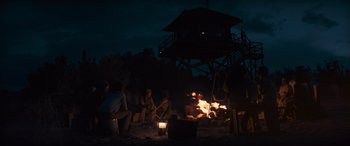Movie still from “Logan” (2017), directed by James Mangold – A group of people sitting around a fire at night; Wide shot, Low angle