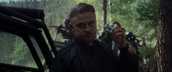 Movie still from “Logan” (2017), directed by James Mangold – A man holding a cell phone while standing next to a forest; Close Up shot, Over the shoulder angle