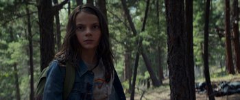 Movie still from “Logan” (2017), directed by James Mangold – A young girl standing in the middle of a forest; Close Up shot, Low angle