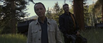 Movie still from “Logan” (2017), directed by James Mangold – Two men are standing in a wooded area holding guns; Medium shot, Over the shoulder angle