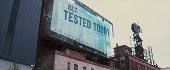Movie still from “Looper” (2012), directed by Rian Johnson – An advertisement on the side of a building that reads " get tested today "; Extreme Wide shot, Low angle