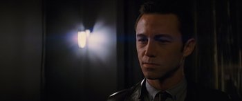 Movie still from “Looper” (2012), directed by Rian Johnson – A person wearing a suit and tie; Close Up shot, Over the shoulder angle