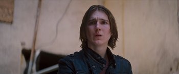 Movie still from “Looper” (2012), directed by Rian Johnson – A man with long brown hair wearing a leather jacket; Close Up shot, Low angle