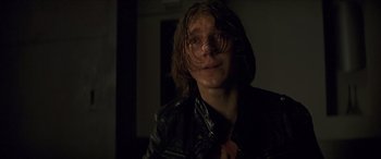 Movie still from “Looper” (2012), directed by Rian Johnson – A man with long hair wearing a leather jacket; Close Up shot, Low angle