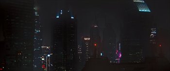 Movie still from “Looper” (2012), directed by Rian Johnson – A view of a city at night from a hill; Extreme Wide shot, Low angle