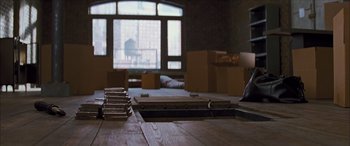 Movie still from “Looper” (2012), directed by Rian Johnson – A room filled with furniture and boxes on top of the floor; Wide shot, High angle