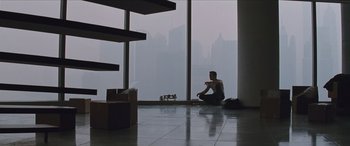 Movie still from “Looper” (2012), directed by Rian Johnson – A man sitting on the floor in front of a large window; Wide shot, High angle