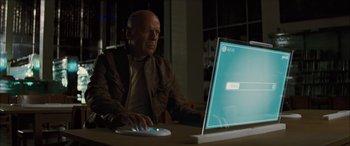Movie still from “Looper” (2012), directed by Rian Johnson – A man sitting in front of an open laptop computer; Medium shot, Over the shoulder angle