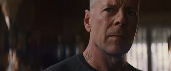 Movie still from “Looper” (2012), directed by Rian Johnson – A person with a tattoo on his neck; Close Up shot, Low angle
