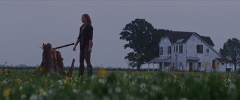 Movie still from “Looper” (2012), directed by Rian Johnson – A woman is walking through a field with a knife; Wide shot, Low angle
