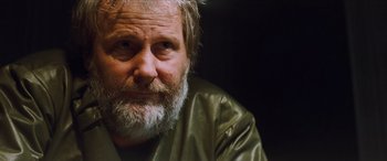 Movie still from “Looper” (2012), directed by Rian Johnson – An older man with a beard and a green jacket; Close Up shot, Over the shoulder angle