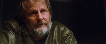 Movie still from “Looper” (2012), directed by Rian Johnson – An older man with a beard and a green jacket; Close Up shot, Over the shoulder angle