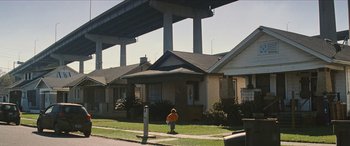Movie still from “Looper” (2012), directed by Rian Johnson – A boy in an orange jacket standing on the sidewalk; Extreme Wide shot, Low angle