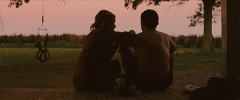 Movie still from “Looper” (2012), directed by Rian Johnson – A man and a woman sitting on the ground; Medium shot, Over the shoulder angle