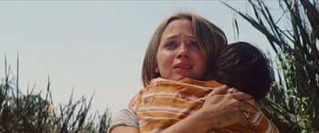Movie still from “Looper” (2012), directed by Rian Johnson – A young woman holding a baby in her arms and crying; Close Up shot, Low angle