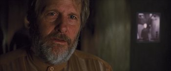 Movie still from “Looper” (2012), directed by Rian Johnson – An older man with a beard looking at the camera; Close Up shot, Over the shoulder angle