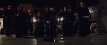 Movie still from “Looper” (2012), directed by Rian Johnson – A group of men standing in a dark room; Wide shot, High angle
