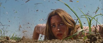 Movie still from “Looper” (2012), directed by Rian Johnson – A woman laying on the ground looking at the camera; Close Up shot, Low angle