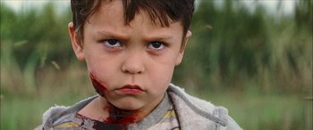 Movie still from “Looper” (2012), directed by Rian Johnson – A young boy with blood on his face; Close Up shot, Over the shoulder angle