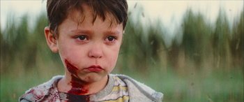 Movie still from “Looper” (2012), directed by Rian Johnson – A little boy with blood all over his face; Close Up shot, High angle