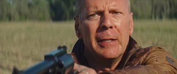 Movie still from “Looper” (2012), directed by Rian Johnson – A person holding a gun; Close Up shot, Over the shoulder angle