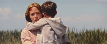 Movie still from “Looper” (2012), directed by Rian Johnson – A woman and a boy are hugging in a field; Close Up shot, Low angle