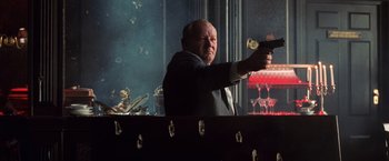 Movie still from “Lord of War” (2005), directed by Andrew Niccol – A man holding a gun in his hand; Medium shot, Over the shoulder angle