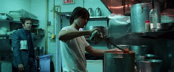 Movie still from “Lord of War” (2005), directed by Andrew Niccol – A man in white shirt cooking food inside of a kitchen; Medium shot, Low angle