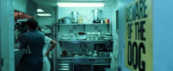 Movie still from “Lord of War” (2005), directed by Andrew Niccol – A person in a kitchen with a lot of dishes on the shelves; Medium shot, Low angle