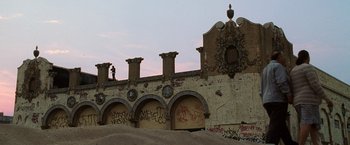 Movie still from “Lord of War” (2005), directed by Andrew Niccol – A building that has graffiti all over it; Extreme Wide shot, Low angle