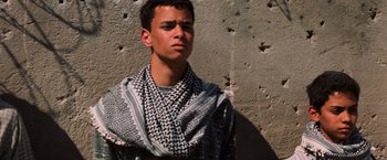 Movie still from “Lord of War” (2005), directed by Andrew Niccol – A young man wearing a keffiyeh standing in front of a wall; Close Up shot, Low angle