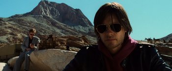 Movie still from “Lord of War” (2005), directed by Andrew Niccol – A person wearing a jacket and sunglasses; Close Up shot, Over the shoulder angle