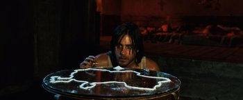 Movie still from “Lord of War” (2005), directed by Andrew Niccol – A man sitting at a table with a knife in his hand; Close Up shot, High angle