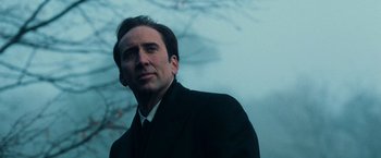 Movie still from “Lord of War” (2005), directed by Andrew Niccol – A man in a black suit and white shirt looking to his left; Close Up shot, Low angle