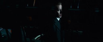 Movie still from “Lord of War” (2005), directed by Andrew Niccol – A man wearing a suit and tie standing in a dark room; Close Up shot, Low angle