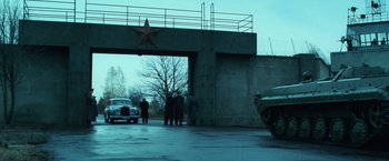 Movie still from “Lord of War” (2005), directed by Andrew Niccol – A group of people standing in front of an overpass; Extreme Wide shot, Low angle