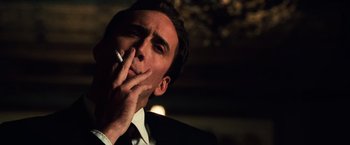 Movie still from “Lord of War” (2005), directed by Andrew Niccol – A person wearing a suit smoking a cigarette; Close Up shot, Low angle