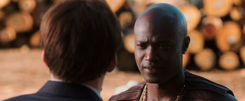 Movie still from “Lord of War” (2005), directed by Andrew Niccol – A man with a bald head talking to another man in a suit; Close Up shot, Over the shoulder angle