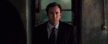 Movie still from “Lord of War” (2005), directed by Andrew Niccol – A man wearing a suit and tie in front of a window; Close Up shot, Low angle