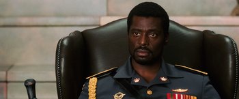 Movie still from “Lord of War” (2005), directed by Andrew Niccol – A person sitting in a chair wearing a uniform; Close Up shot, Low angle
