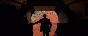 Movie still from “Lord of War” (2005), directed by Andrew Niccol – A man standing in front of a dirt road; Extreme Wide shot, Over the shoulder angle