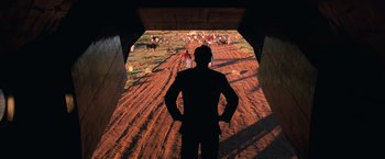 Movie still from “Lord of War” (2005), directed by Andrew Niccol – A man standing in front of an open gate; Wide shot, Low angle