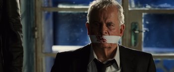 Movie still from “Lord of War” (2005), directed by Andrew Niccol – An older man with a piece of paper over his mouth; Close Up shot, Over the shoulder angle