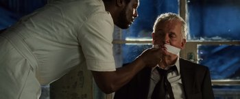 Movie still from “Lord of War” (2005), directed by Andrew Niccol – A man in white shirt and tie brushing another man's teeth; Close Up shot, Over the shoulder angle