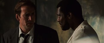 Movie still from “Lord of War” (2005), directed by Andrew Niccol – Two men in suits talking to each other in the dark; Close Up shot, Over the shoulder angle