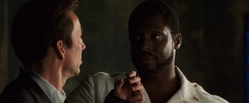 Movie still from “Lord of War” (2005), directed by Andrew Niccol – Two men are talking to each other in a dark room; Close Up shot, Over the shoulder angle