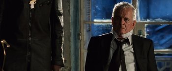 Movie still from “Lord of War” (2005), directed by Andrew Niccol – A man in a suit and tie next to a window; Close Up shot, Low angle