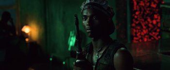 Movie still from “Lord of War” (2005), directed by Andrew Niccol – A man holding a gun while wearing a hat; Close Up shot, Low angle