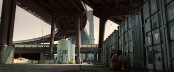 Movie still from “Lord of War” (2005), directed by Andrew Niccol – Two men sitting under an overpass with a bird standing on one of them; Extreme Wide shot, Low angle