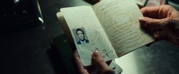 Movie still from “Lord of War” (2005), directed by Andrew Niccol – A person holding an open passport with a picture of a man; Extreme Close Up shot, Overhead angle